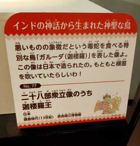 「世界探検の旅」展、No.77「二十八部衆立像のうち迦楼羅王」のイラスト付き解説パネル